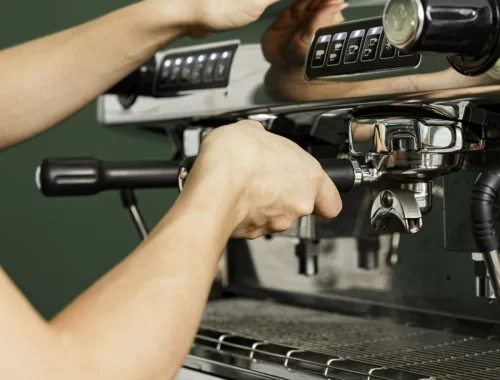 Foto mostrando as mãos de um barista preparando café espresso em máquina profissional para cafeteria